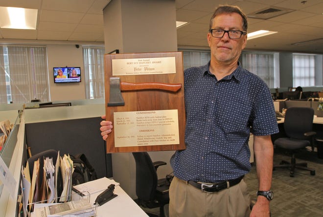 Retiring editor Peter Phipps in The Journal newsroom with "The First Annual Bert Ely Hatchet Award" given to him by then-Gov. Bruce Sundlun. [The Providence Journal / Steve Szydlowski]