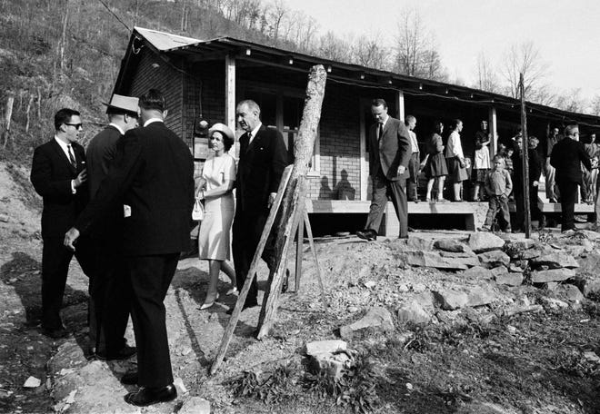 This April 24, 1964, file photo shows President Lyndon Johnson and his wife, Lady Bird, center left, leave the home in Inez, Ky., of Tom Fletcher, a father of eight who told Johnson he'd been out of work for nearly two years. The president visited the Appalachian area in Eastern Kentucky to see conditions firsthand and announce his War on Poverty from the Fletcher porch.
