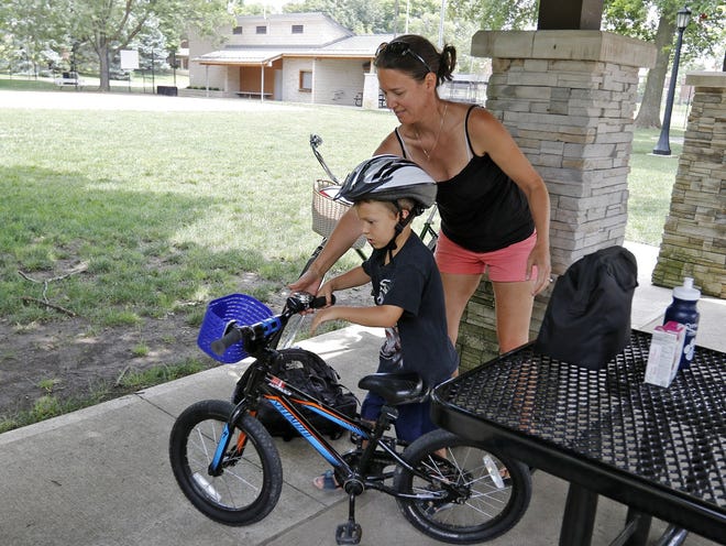 Brenda Young helps her son Zachary Young, 5, get ready to ride his bike at Pierce Field in Grandview Heights. She supports the legislation Grandview Heights City Council will be discussing at their Monday meeting, which would require every person under 18 years old to wear a helmet when riding bicycle. [Barbara J. Perenic/Dispatch]