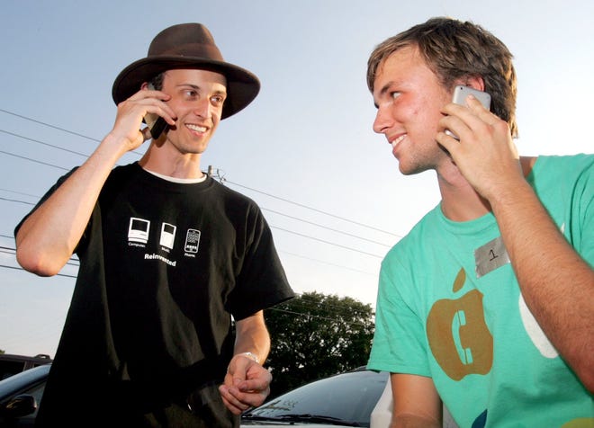 Kenny Peoples, left, and Kevin Kelly show off their new Apple iPhones in Panama City in June 2007. They both spent the night outside of the AT&T store on 23rd Street waiting for the phones. [ANDREW WARDLOW/NEWS HERALD FILE PHOTO]