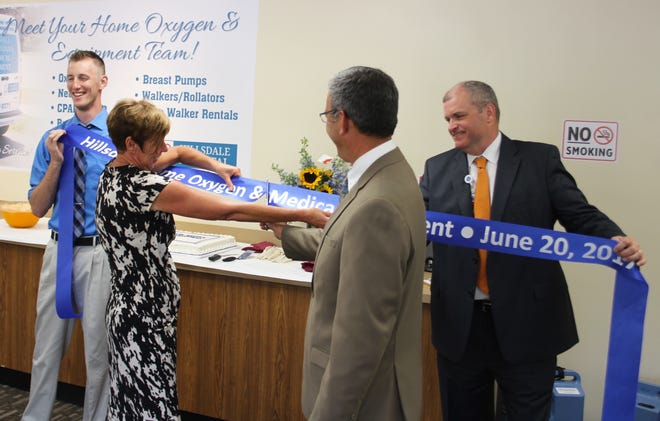 Ryan Kast, Sylvia Roberts and Duke Anderson (left to right) hold the ribbon while Hillsdale Hospital Chairman Greg Bailey gives it a grand opening snip on Tuesday afternoon. [ANDREW KING PHOTO]