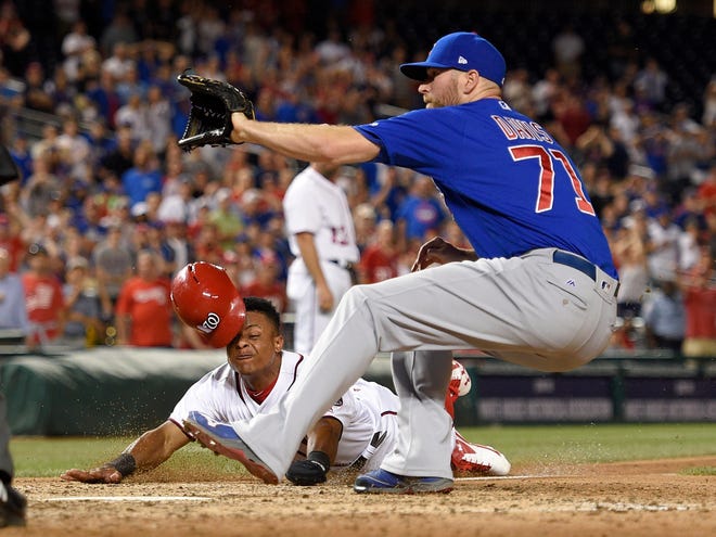 Washington Nationals Wilmer Difo, bottom, slides home on a wild pitch against Chicago Cubs relief pitcher Wade Davis (71) during the ninth inning of a baseball game, Monday, June 26, 2017, in Washington. Diff scored on the play. The Cubs won 5-4. (AP Photo/Nick Wass)