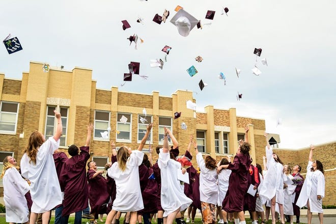 Dundee graduates gather in front of the school to toss their mortarboards.