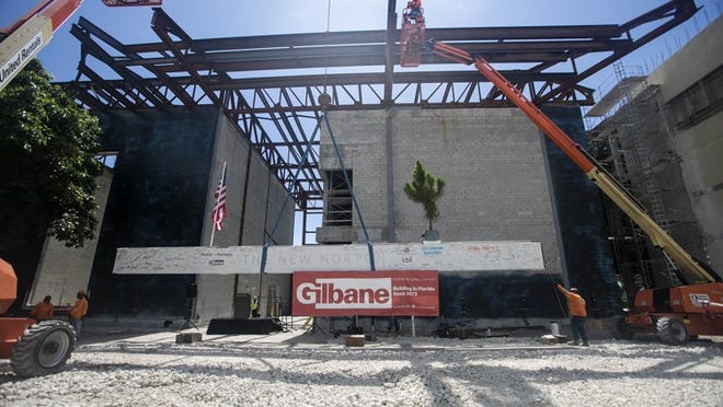 A crane lifted a signed beam to its position 54 feet above the future main entrance Tuesday at the topping out ceremony for the Norton Museum’s expansion. The evergreen on the beam is a nod to the Scandinavian tradition of placing a tree atop a new building. (Bruce R. Bennett / Daily News)