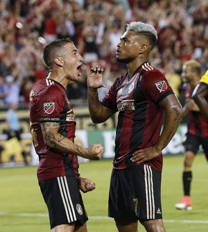 Atlanta United forward Josef Martinez, left, is fired up over his goal that finished the scoring in a 3-1 home win over Crew SC on June 17. Midfielder Carlos Carmona is more restrained. [John Bazemore/The Associated Press]
