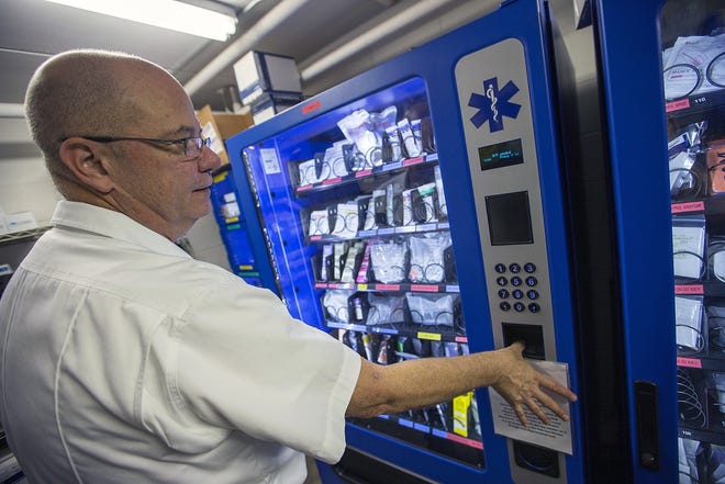 Jackson Township Fire Department Capt. Bill Dolby demonstrates the use of a fingerprint ID security measure on a vending machine that distributes medications and first-aid supplies. Dolby said the machines have cut the cost of expired medications from $4,000 per month to less than $1,000.
