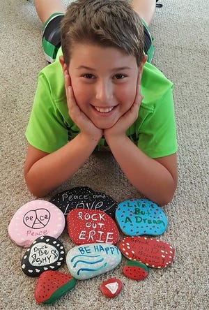 Rome Cicero, 11, shows off some of the rocks he and his family have painted as part of their Rock Out Erie! project. [SARAH GRONER/CONTRIBUTED PHOTO]