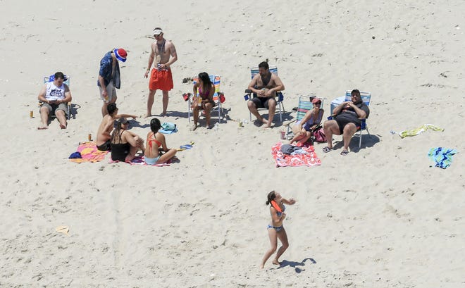In this Sunday photo, New Jersey Gov. Chris Christie, right, uses the beach with his family and friends at the governor's summer house at Island Beach State Park in New Jersey. Christie is defending his use of the beach, closed to the public during New Jersey's government shutdown, saying he had previously announced his vacation plans and the media had simply "caught a politician keeping his word." [ANDREW MILLS/NJ ADVANCE MEDIA via AP]