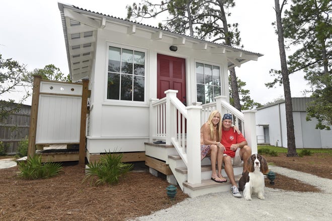 Mary McGuigan and John Walden pose with their dog, "Dude," on the porch of the small cottage they built in the small Gulf Coast community of Seagrove Beach in the northwest Florida Panhandle. The house, including deck and outdoor shower, is just under 300 square feet in size. [Devon Ravine / Northwest Florida Daily News via AP]