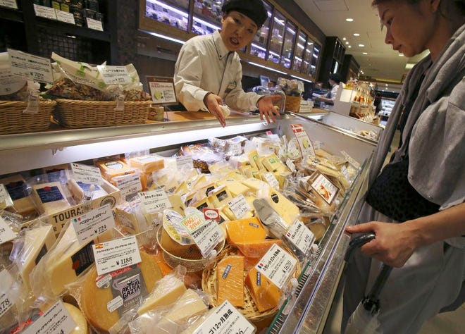 A shopper in Tokyo looks at various types of imported cheese.