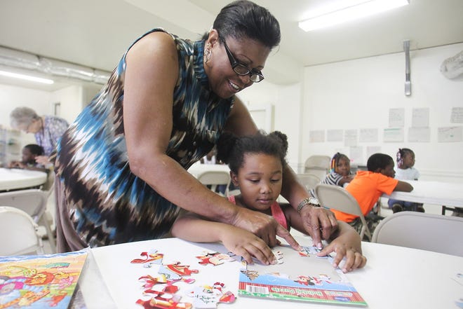 Joyce Smith assists Miracle Jones, 5, with an interactive puzzle at the free lunch and learn program at Faith Harvest Church on Friday morning. [Hannah Dunaway/The Star]