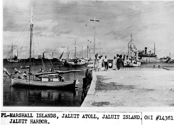 This undated photo discovered in the U.S. National Archives by Les Kinney shows people on a dock in Jaluit Atoll, Marshall Islands. A new documentary film proposes that this image shows aviator Amelia Earhart, seated third from right, gazing at what may be her crippled aircraft loaded on a barge. The documentary “Amelia Earhart: The Lost Evidence,” which airs Sunday, July 9, 2017, on the History channel, argues that Earhart and her navigator, Fred Noonan, crash-landed in the Japanese-held Marshall Islands, were picked up by Japanese military and that Earhart was taken prisoner. (Office of Naval Intelligence/U.S. National Archives via AP)