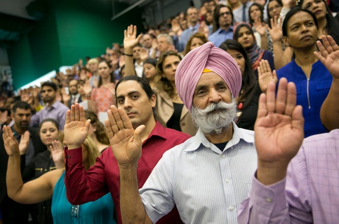 Guillermo Leal, left, of Mexico, and Mohinder Singh, of India, take the oath of citizenship at a naturalization ceremony in Austin, Texas, on Thursday June 29, 2017. Nearly 1,200 people from 98 countries became United States citizens at the ceremony.