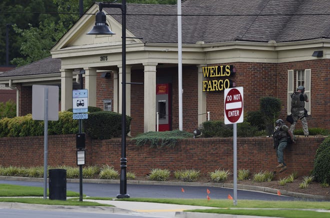 Police officers take up positions outside a Wells Fargo Bank in Marietta, Ga., Friday, July 7, 2017, following reports of man claiming to have a bomb inside the bank. Two people who were in the bank made it out safely after a large military-type vehicle smashed its way through a back wall of the bank building. (AP Photo/Mike Stewart)