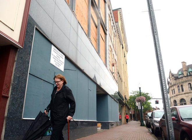 Kathleen Kaiser, of Norwich, walks by the boarded-up Reid & Hughes building Friday in downtown Norwich. When asked if she would like to see apartments there she said "Why not? The Wauregan worked out great." [John Shishmanian/ NorwichBulletin.com]