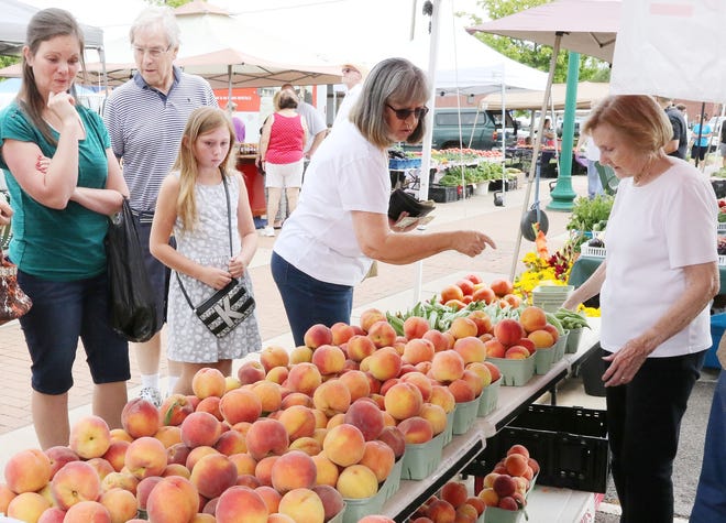 Jewel Anderson, right, helps customers pick out freshly harvested Gloria yellow peaches Saturday, July 8, 2017, at Fort Smith's downtown Farmers Market on Garrison Avenue. [JAMIE MITCHELL/TIMES RECORD]