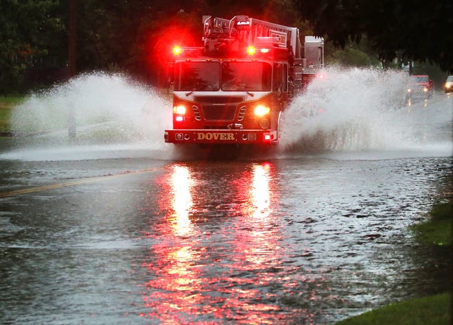 A Dover ladder truck splashes down North Broadway to help close off the flooded intersections following a storm Monday evening in New Philadelphia. (TimesReporter.com / Pat Burk)