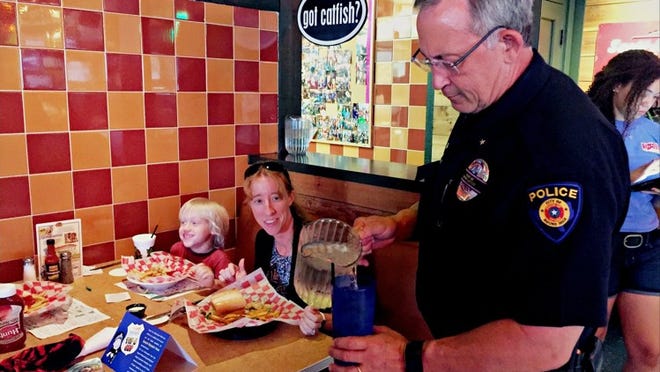 Round Rock Police Cmdr. Jim Stuart serves water to guests at Razoo’s Cajun Restaurant during the “Tip a Cop” event. Photo by Ariana Garcia