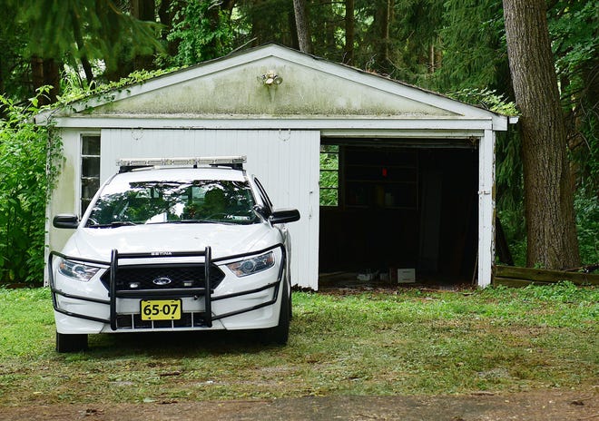 A police cruiser sits in front of a garage where in investigators found Tom Meo's car. Meo is one of the four missing men.
