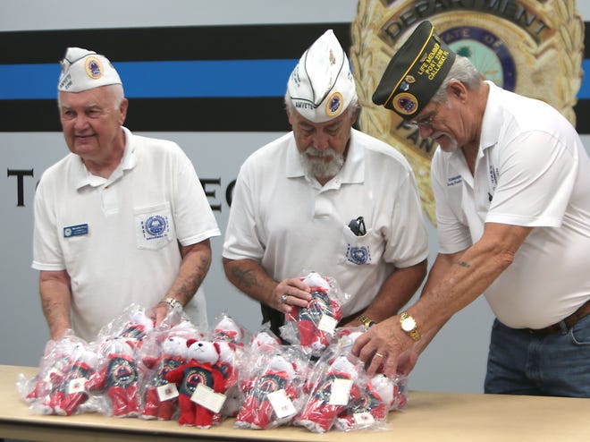 From left, Marlin Coy, Robb Fry and Rocky Bradford look over stuffed animals Wednesday at the Panama City Police Department. The officers give the bears to children to comfort them at traumatic events. [PATTI BLAKE/THE NEWS HERALD]