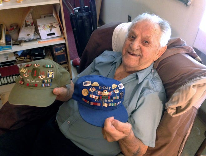 In this Tuesday, July 11, 2017 photo, World War II veteran Leo Heroux, 93, holds his D-Day hats with pins from anniversaries of the June 6, 1944, invasion and his service ribbons at his home in Central Falls, R.I. Heroux fought in Europe with an engineer combat battalion. He's one of three Rhode Island veterans who will receive France's highest distinction, the Legion of Honor, during a ceremony Friday in Providence. (AP Photo/ Jennifer McDermott) ORG XMIT: RPJM202