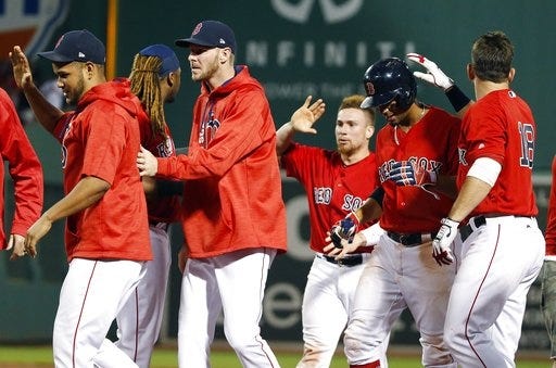 The Red Sox celebrate after winning 5-4 over the Yankees on a walk by Andrew Benintendi with bases loaded during the ninth inning at Fenway Park on Friday night. [AP Photo/Michael Dwyer]