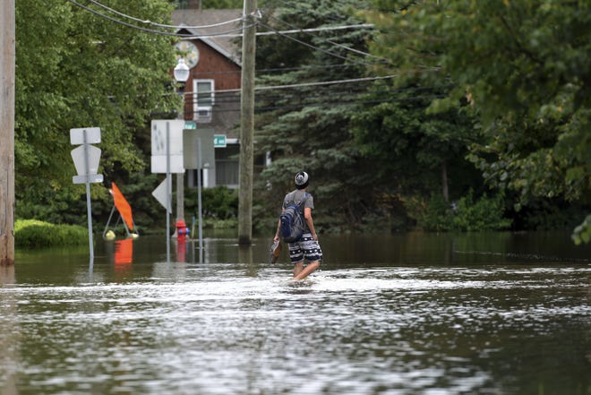A man walks on a flooded street Friday, July 14, 2017, in Gurnee. Illinois officials said Friday that several thousand buildings have been affected by "unprecedented" flooding north of Chicago, and the damage is expected to worsen this weekend as water flows down rivers into the state from Wisconsin. [G-JUN YAM THE ASSOCIATED PRESS]