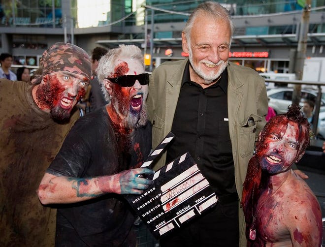 In this Sept. 12, 2009, photo, director George Romero poses with fans dressed as zombies after accepting a special award during the Toronto International Film Festival in Toronto. (Darren Calabrese/The Canadian Press via AP, File)