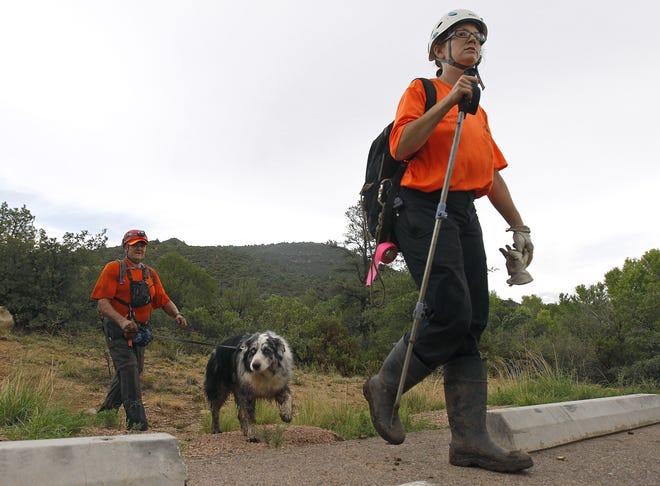 Members of the Tonto Rim Search and Rescue team exit a section of forest after searching along the banks of the East Verde River for victims of a flash flood, Sunday, July 16, 2017, in Payson, Ariz. Search and rescue crews, including 40 people on foot and others in a helicopter, have recovered bodies of children and adults, some as far as two miles down the river after Saturday's flash flooding poured over a popular swimming area inside the Tonto National Forest in central Arizona. (AP Photo/Ralph Freso)