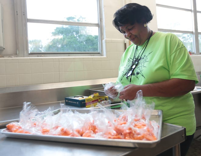 Piquieta White assembles bags of carrots Tuesday at the A.D. Harris Learning Village. They were added to lunch bags given for free to area children through the Praise and Empowerment Center. [PATTI BLAKE/THE NEWS HERALD]