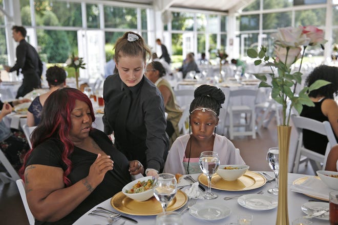 Katelin Decraene, center, gives Trishell Crawford and her daughter Jacqueline Crawford, from Dayspring, salads at a reception at the Ritz Charles, Saturday, July 15, 2017. Sarah Cummins called off her wedding which was supposed to be this day. Cummins decided to bring purpose to the couple's pain by inviting area homeless to enjoy the reception. (Kelly Wilkinson/The Indianapolis Star via AP)