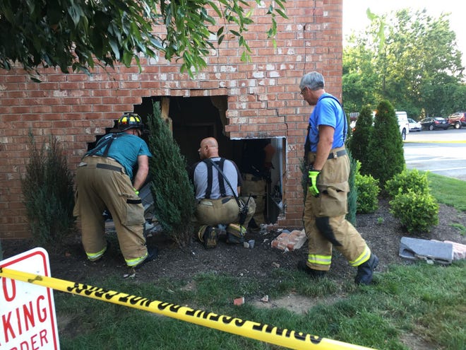 Members of the Warminster Fire Department inspect a hole in an apartment building left behind after an SUV crashed into its side Wednesday, July 19, 2017.