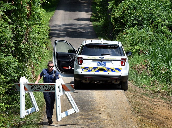 A police officer carries a barricade to close off the drive to the DiNardo property on Lower York Road in Solebury on Thursday, July 20, 2017.