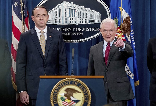 Attorney General Jeff Sessions, right, accompanied by Deputy Attorney General Rod Rosenstein, left, calls on a member of the media at a news conference to announce an international cybercrime enforcement action at the Department of Justice Thursday in Washington. [ANDREW HARNIK/ASSOCIATED PRESS]