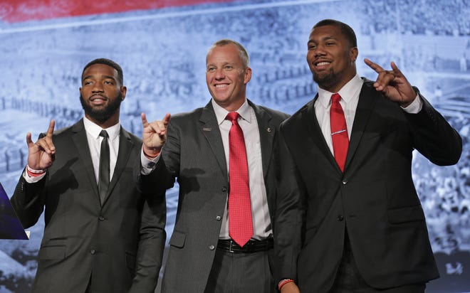 North Carolina State head coach Dave Doeren, center, gives the "Wolfpack" sign as he poses for a photo with players Jaylen Samuels, left, and Bradley Chubb, right, during the Atlantic Coast Conference NCAA college football media day in Charlotte, N.C., Thursday, July 13, 2017. (AP Photo/Chuck Burton)