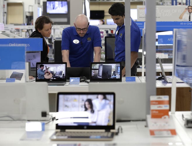 Employees assist a customer with a computer at Best Buy in Cary, North Carolina. Hands-on assistance is one of the draws in its fight with e-commerce. [AP / Gerry Broome]