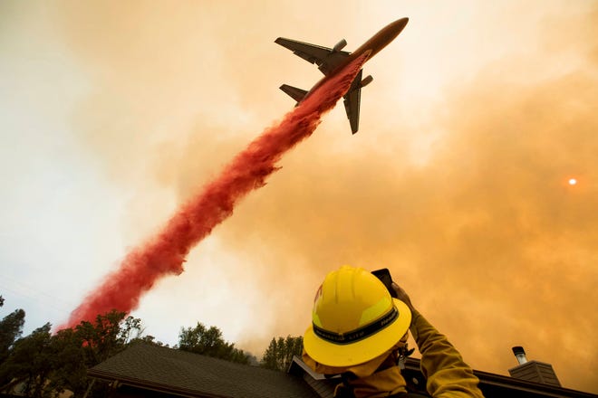 An air tanker drops retardant while battling a wildfire near Mariposa, Calif., Wednesday, July 19, 2017. The fire has forced thousands of people from homes in and around a half-dozen small communities, officials said. (AP Photo/Noah Berger)