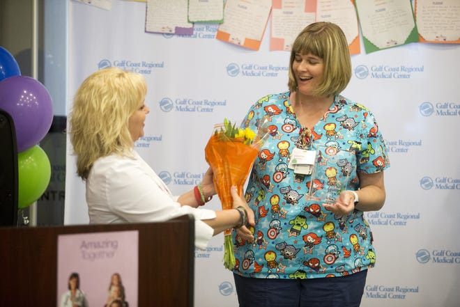 Pam Norman, the director of children's services at Gulf Coast Regional Medical Center, gives pediatric nurse Courtney Hartzer the Amazing Together award. [JOSHUA BOUCHER/THE NEWS HERALD]
