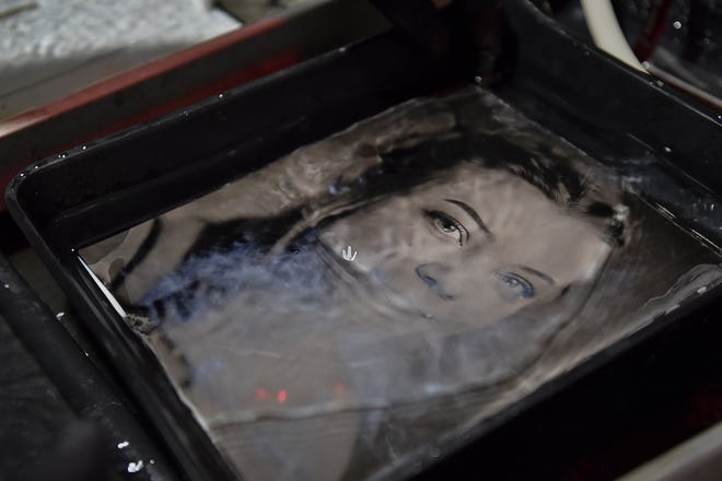 The image of Emily Williams, daughter of a family friend, appears as the black glass photo plate is bathed in a fixer.