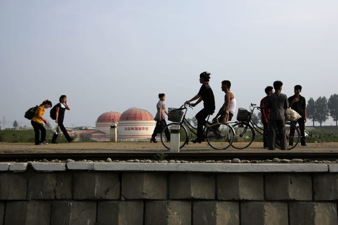 North Koreans walk while some cycle past a factory dome with Korean words painted on its side which read "First priority: self development" at the end of a work day on Thursday, July 20, 2017, in Hamhung, North Korea. Hamhung is North Korea's second largest city. (AP Photo/Wong Maye-E)