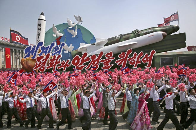 People wave flags and plastic flowers April 15 in Kim Il Sung Square in Pyongyang, North Korea, as a float with model missiles and rockets with the words “For Peace and Stability in the World” is paraded across. Hawaii is rolling out a civil defense plan in case of a North Korean missile attack. [WONG MAYE-E/ASSOCIATED PRESS FILE PHOTO]