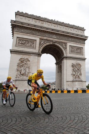 Britain’s Chris Froome, wearing the overall leader’s yellow jersey, is followed by teammate Colombia’s Sergio Henao Montoya, as they pass the Arc de Triomphe during the twenty-first and last stage of the Tour de France cycling race over 103 kilometers (64 miles) with start in Montgeron and finish in Paris, France, Sunday, July 23, 2017. (AP Photo/Christophe Ena)