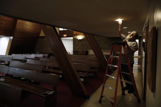 Craig Wollenslegel of St. Edwards Episcopal Church on the East Side installs energy-saving LED lightbulbs in the church. Several central Ohio churches see saving energy in their buildings as part of their mission to protect the environment. [Kyle Robertson/Dispatch]