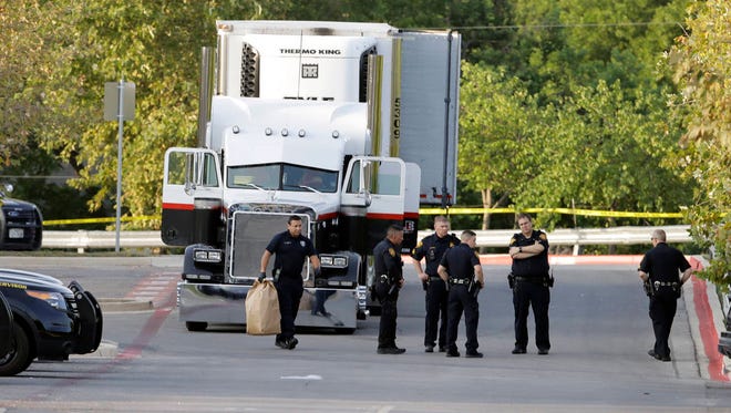 San Antonio police officers investigate the scene Sunday, July 23, 2017, where eight people were found dead in a tractor-trailer loaded with at least 30 others outside a Walmart store in stifling summer heat in what police are calling a horrific human trafficking case, in San Antonio. (Associated Press)