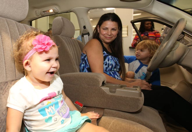 Aubree Battillo, 2, left, checks out her family's new car, with her mother, Jennifer, and brother, Brandon, 4, after Tom Formanek, the president and CEO of Jenkins Automotive Group, donated the 2002 Chevrolet Impala to them through a partnership with the Community With A Heart Program at Jenkins Hyundai on Southwest College Road in Ocala on Wednesday. [Bruce Ackerman/Staff photographer]