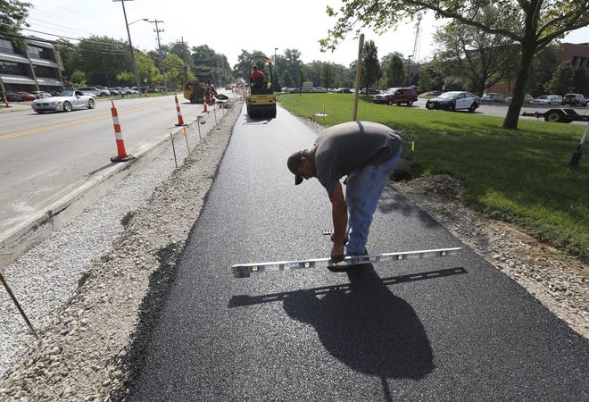 Toby Crabtree, an employee of Strawser Paving Company, checks the cross slope of the new bike path along West 5th Avenue. The trail will connect Arlington Avenue and the Scioto Trail. [Eric Albrecht/Dispatch]