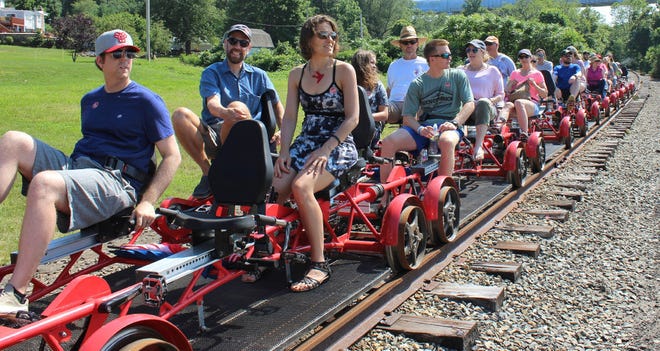A Rail Explorers tour stops to admire the view by the Mount Hope Bridge in Portsmouth. Rail Explorers opened in Portsmouth in April as part of the Newport and Narragansett Bay Railroad. Visitors can ride a rail bike and travel six miles along tracks that were once part of the Old Colony Railroad. (AP Photo/Jennifer McDermott)