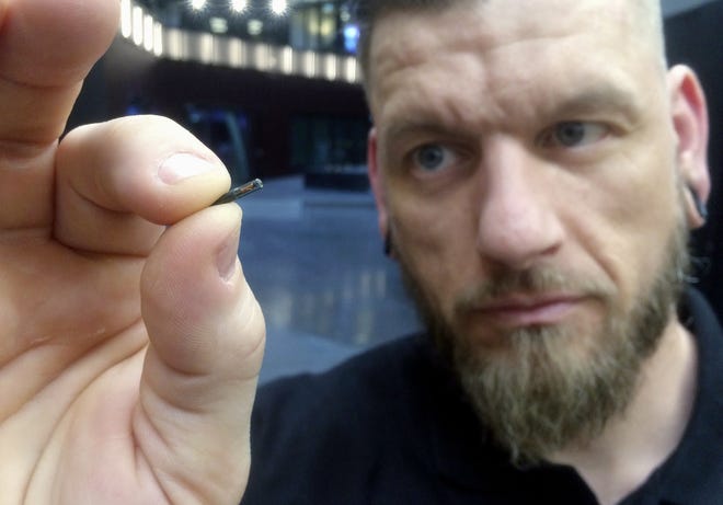 FILE - In this March 14, 2017, file photo, Jowan Osterlund from Biohax Sweden, holds a small microchip implant, similar to those implanted into workers at the Epicenter digital innovation business center during a party at the co-working space in central Stockholm. Three Square Market in River Falls, Wis., is partnering with Sweden's BioHax International, offering to microchip its employees, enabling them to open doors, log onto their computers and purchase break room snacks with a simple swipe of the hand. More than 50 employees are voluntarily getting implants Aug. 1 at what the company is calling a "chip party" at its River Falls headquarters. (AP Photo/James Brooks, File)