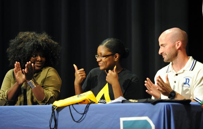 Kiara Felix (seated) gives two big thumbs up during a college scholarship letter of intent signing as her sister, Jennifer, and track coach Tom Trull applaud Wednesday, July 19. [Wicked Local photo/Tom Gorman]
