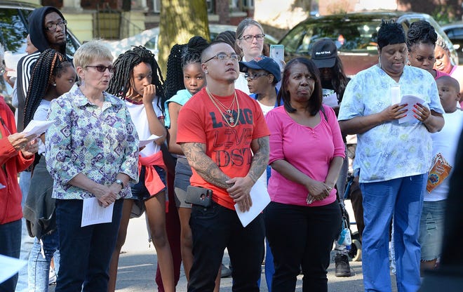 Billy Condon Jr., 28, center, takes a moment of silence with others during a Take Back the Site vigil for homicide victim David Tate in the 1300 block of East 20th Street in Erie Tuesday. Condon said he was a good friend of victim Tate. [GREG WOHLFORD/ERIE TIMES-NEWS]
